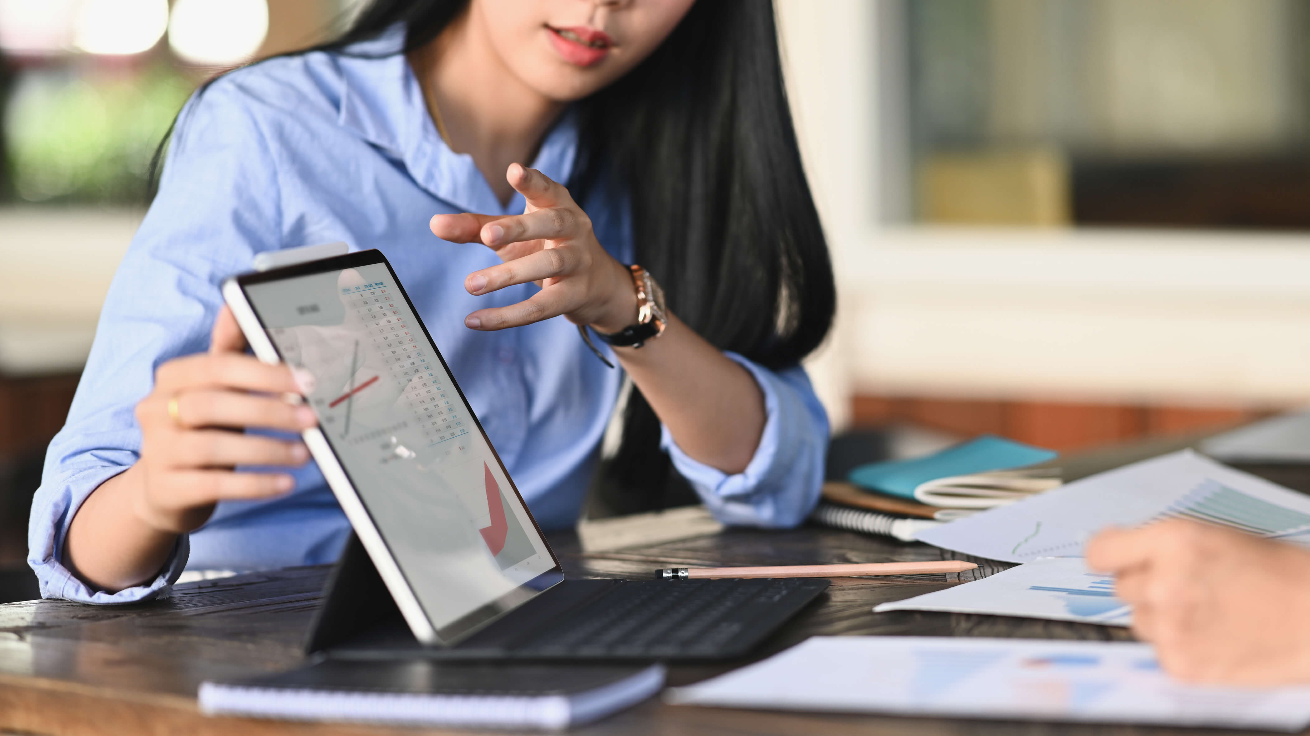 Imagem de mulher segurando um tablet durante apresentação.